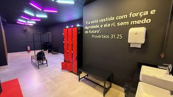 Un baño moderno con pared negra, lavabo blanco y una banca.