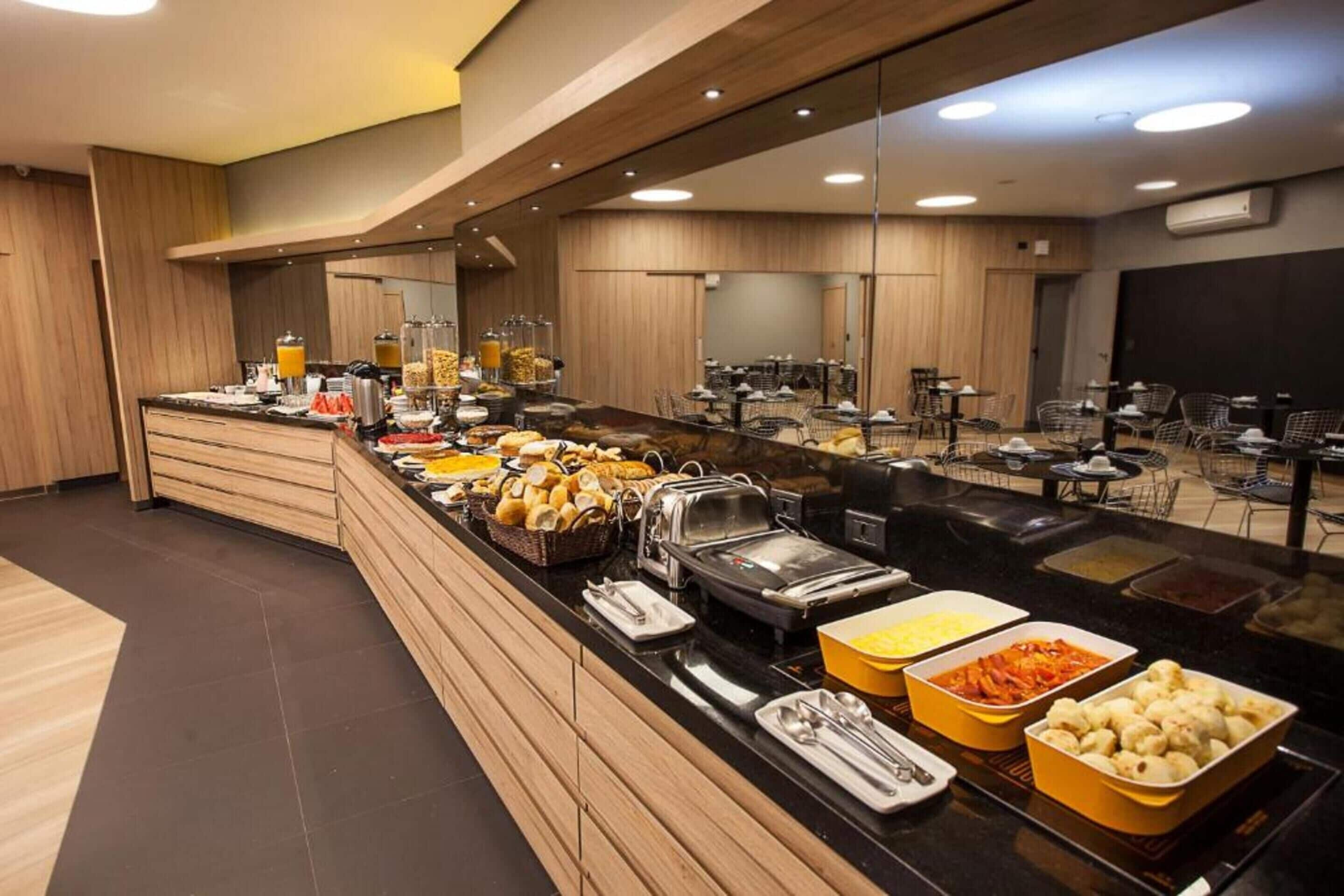 A buffet with various food items and a seating area with tables and chairs.
