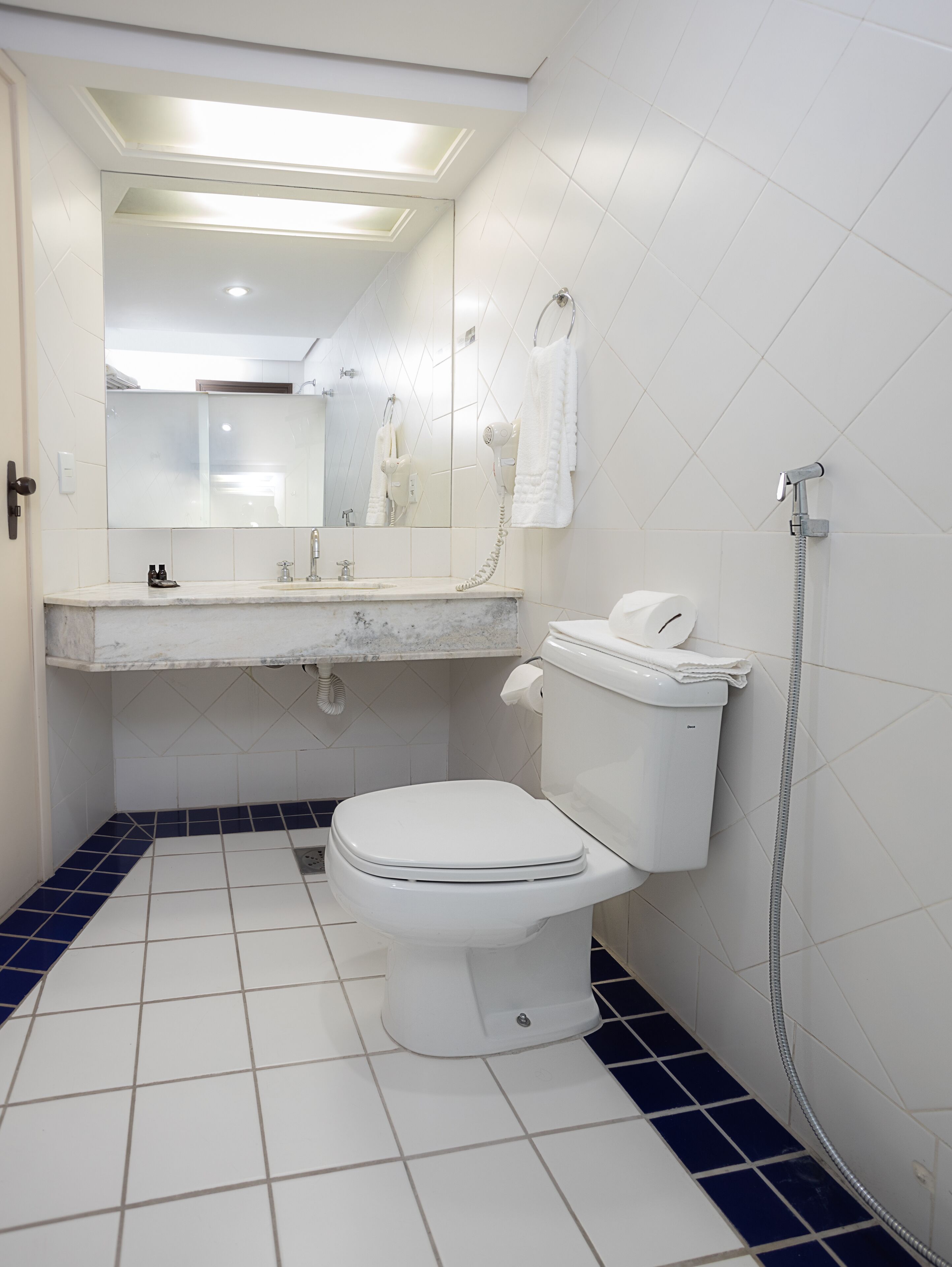 Un baño con inodoro, lavamanos, espejo y ducha.