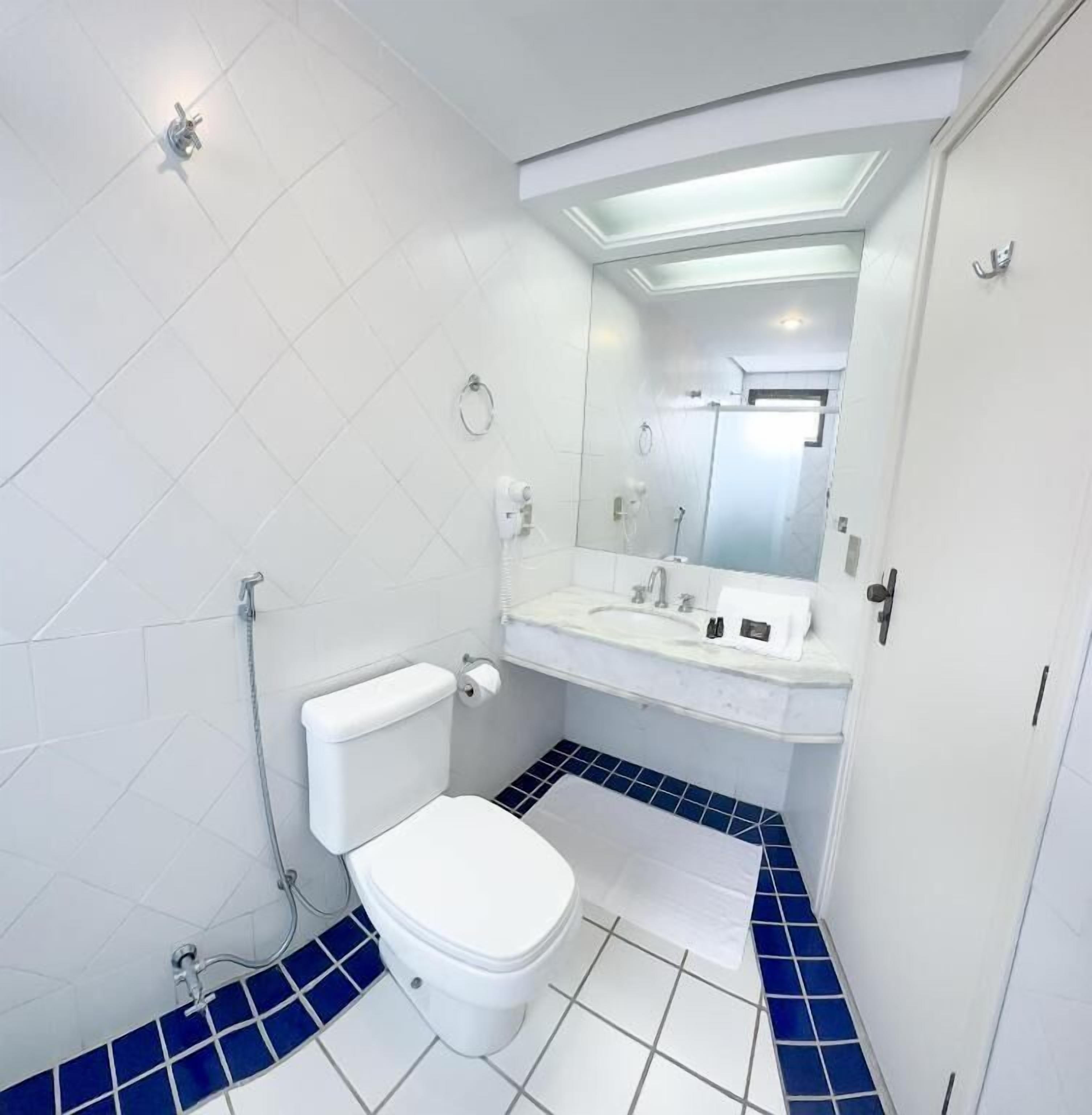 Un baño con inodoro, lavamanos y espejo.
