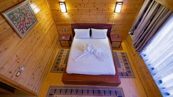 A wooden cabin-style room with a bed, two bedside tables, and a wall-mounted light fixture.