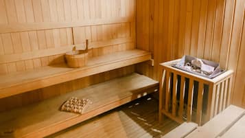 A wooden sauna with benches, a bench with a towel, and a bench with a tray.