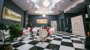 Un vestíbulo de hotel con suelo a cuadros, sillas blancas, una araña de cristal y pinturas en las paredes.