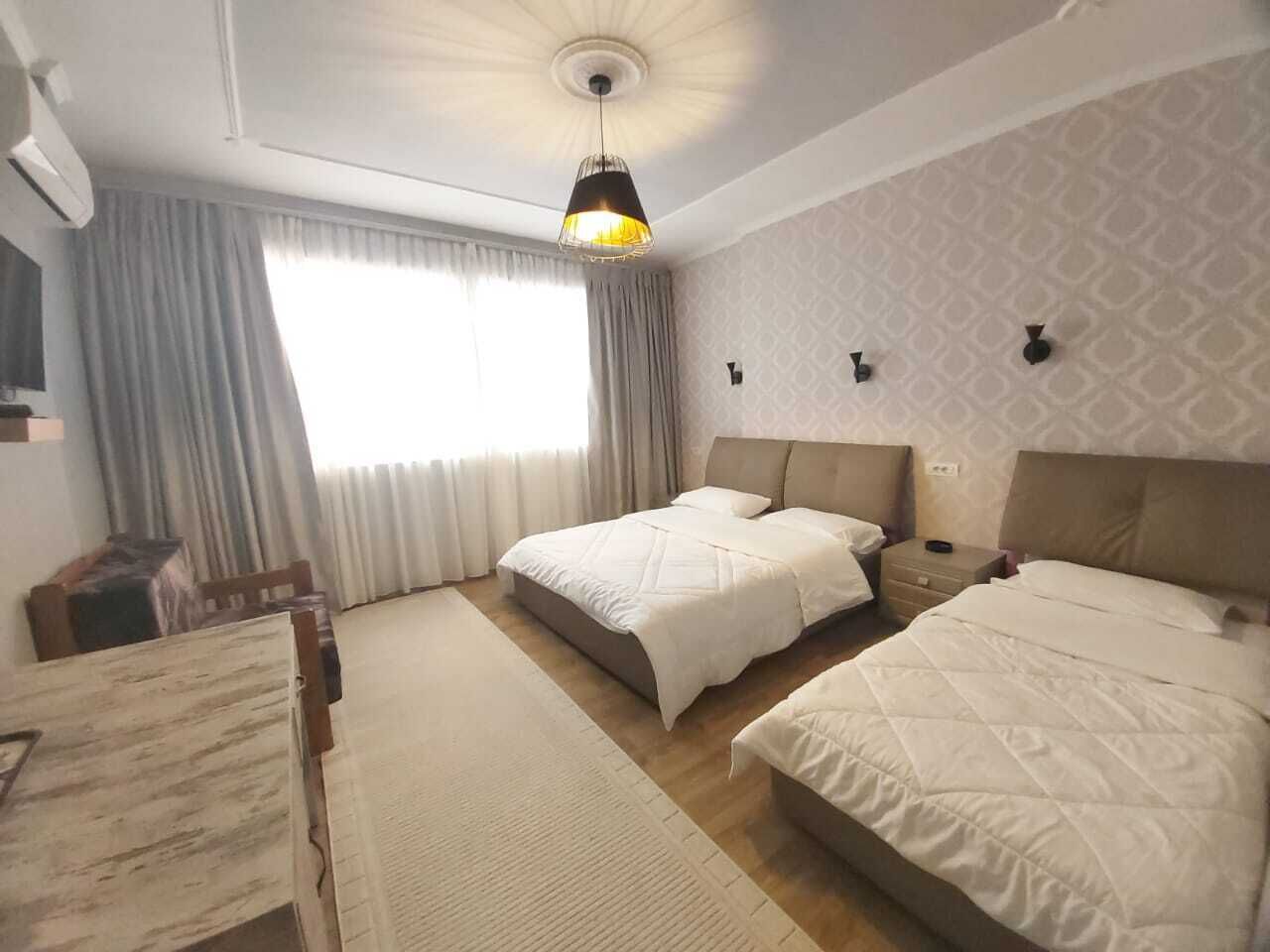 A hotel room with two beds, a desk, and a chair.