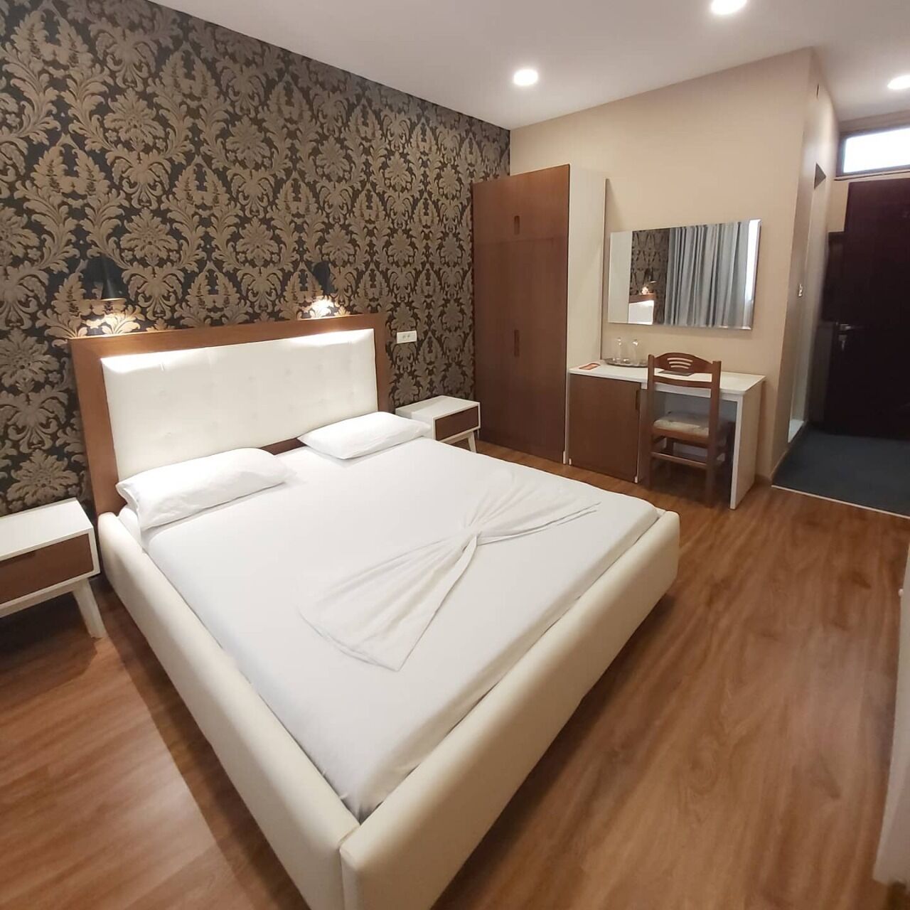 Een hotelkamer met een groot bed, een bureau, een kledingkast en een spiegel.