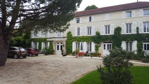 A two-story building with a gravel driveway and parked cars.