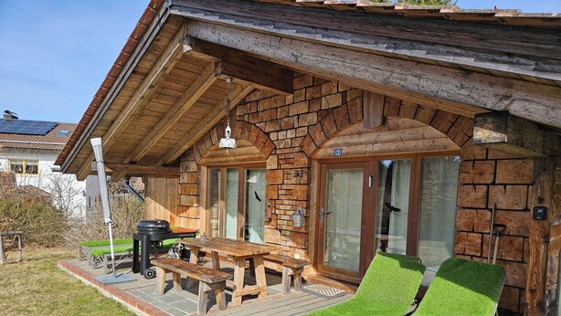 Eine Holzdiele mit einer Terrasse, Sitzgelegenheiten im Freien und einem Grill.