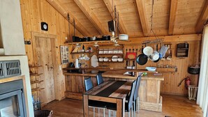 Eine rustikale Holzküche mit Kochinsel, Holzboden und einer an der Decke befestigten Kochgeschirr-Leiter.