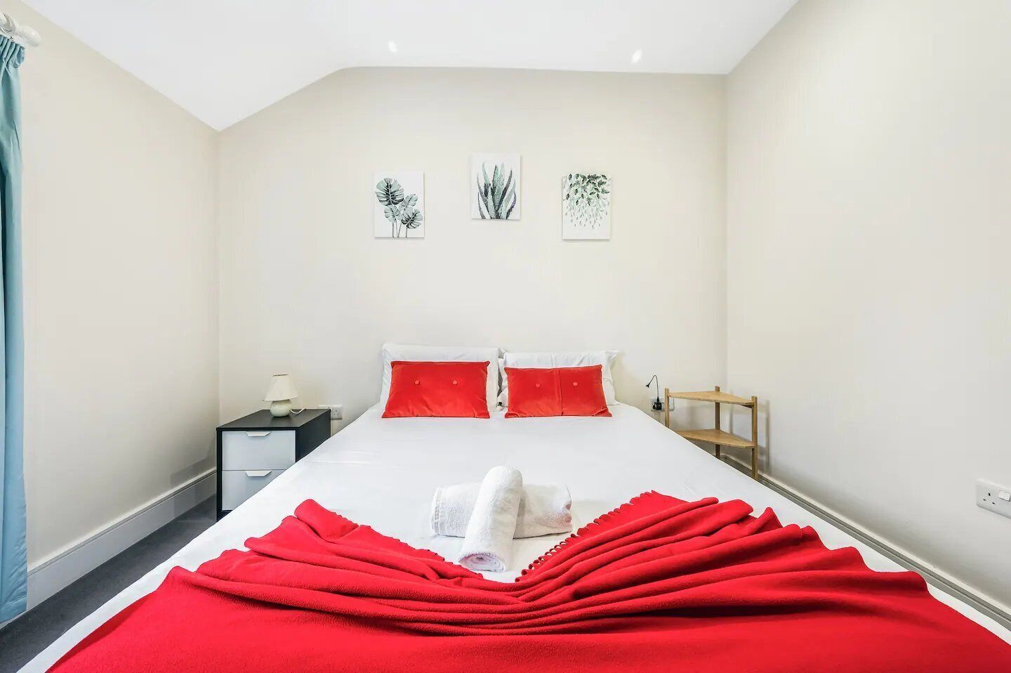 Habitació d'hotel amb llit, una tauleta de nit, una làmpada i una prestatgeria de fusta.