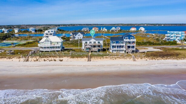 A beachfront property with multiple houses, a pier, and a view of the ocean. - Wright By The Sea - premier 4 bedroom oceanfront home (North Topsail Beach)