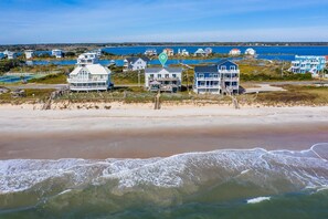 A beachfront property with multiple houses, a pier, and a view of the ocean. - Wright By The Sea - premier 4 bedroom oceanfront home (North Topsail Beach)