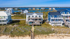 A beachfront property with multiple houses, including a prominent white house with a balcony and a blue house with a deck. - Wright By The Sea - premier 4 bedroom oceanfront home (North Topsail Beach)