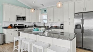A modern kitchen with white cabinets, stainless steel appliances, a granite countertop, and pendant lighting. - Wright By The Sea - premier 4 bedroom oceanfront home (North Topsail Beach)