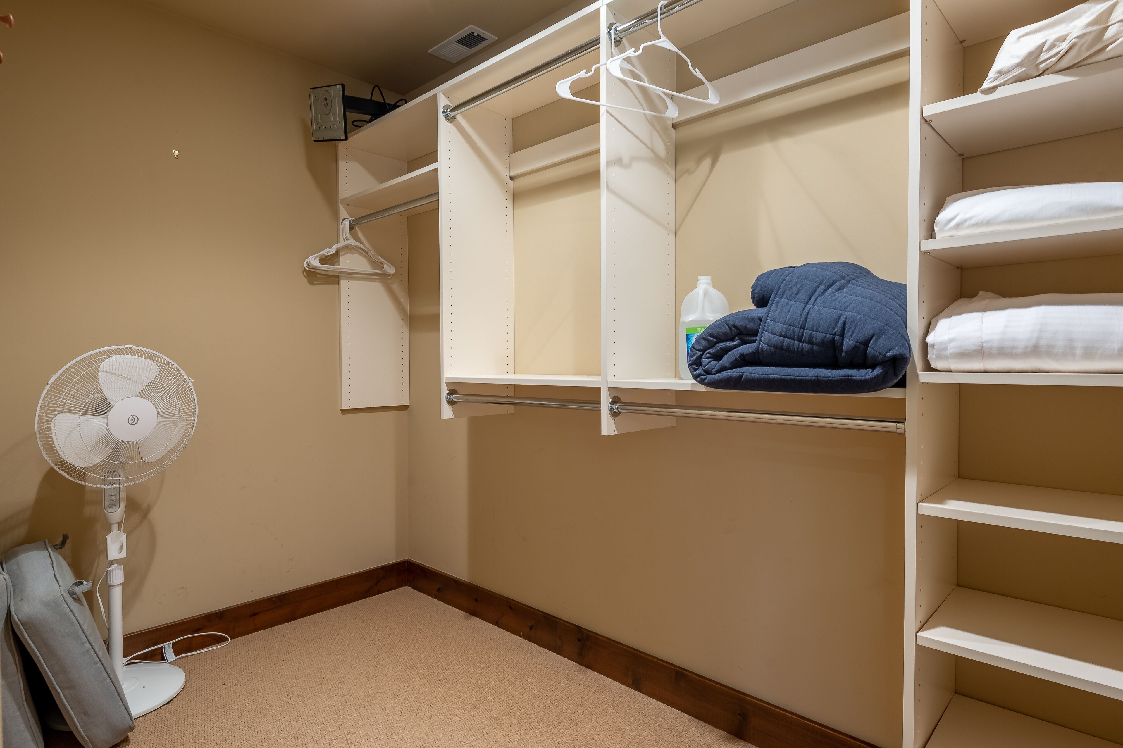 A bunk bed with a white fan and a shelf with a blue blanket.