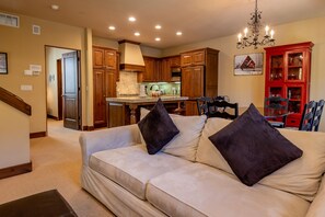 A living room with a beige sofa, dark cushions, and a chandelier.