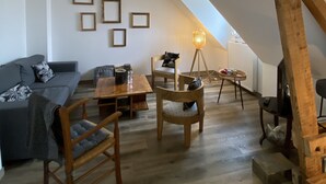 A loft-style living room with a sloped ceiling, wooden furniture, and a floor lamp. - The bookstore, beachfront house facing Tatihou island, feet in the water ! (Reville)