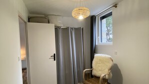 Een slaapkamer met een bed, een stoel, een raam, een deur en een plafondlamp.