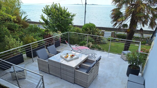 A balcony with a wicker sofa, a table with a tray of food, and a view of the sea. - The bookstore, beachfront house facing Tatihou island, feet in the water ! (Reville)