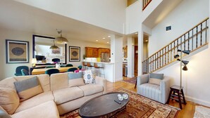 A spacious living area with a large sectional sofa, a dining table, and a kitchen in the background. - Central Park 26- Luxury Tri-Level in Great Location Close to River Run (Ketchum)