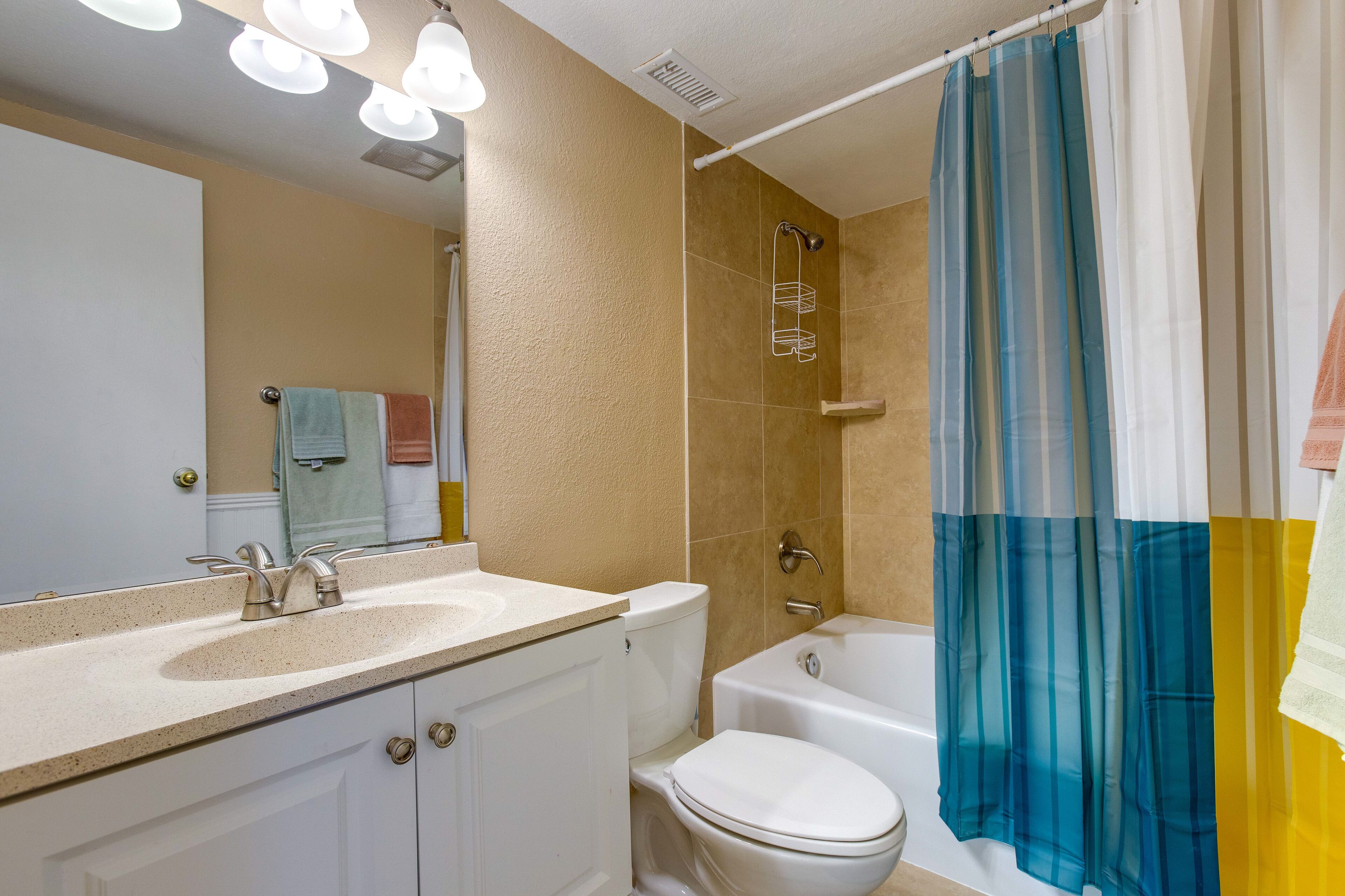 Une salle de bain équipée d’un lavabo, de toilettes, d’une baignoire et d’un rideau de douche.