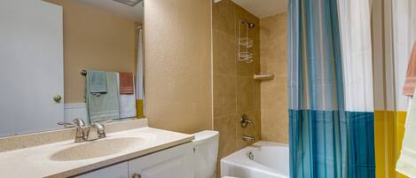 Une salle de bain équipée d’un lavabo, de toilettes, d’une baignoire et d’un rideau de douche.