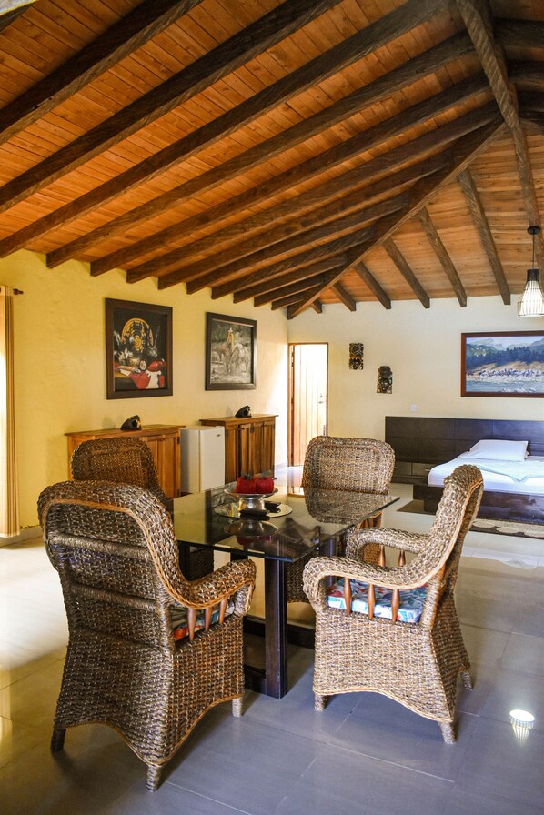 A dining area with wicker chairs, a table, and a ceiling with exposed wooden beams. - Kuma Secret Island - Experience Hotel (Guatapé)