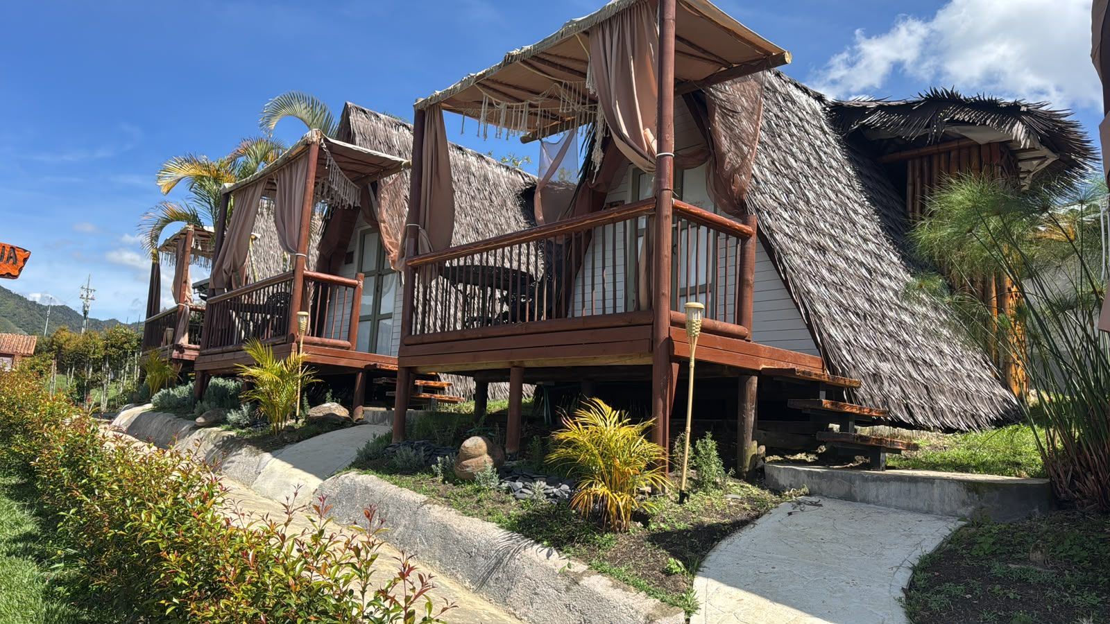 Un resort con cabañas de techo de paja y balcones de madera.