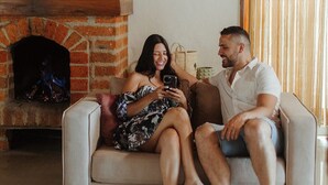 A couple sitting on a sofa in a room with a brick fireplace. - Kuma Secret Island - Experience Hotel (Guatapé)