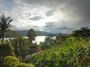 A scenic view of a coastal area with a mountain in the background, a body of water, and lush greenery in the foreground. - Kuma Secret Island - Experience Hotel (Guatapé)