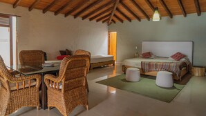 Habitació amb sostre de fusta, un llit amb almoades, una taula amb cadires i una taula rodona petita.