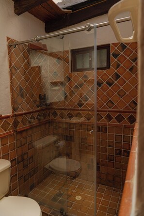 A shower enclosure with a glass door, a tiled wall, and a small window. - Kuma Secret Island - Experience Hotel (Guatapé)