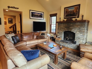 A cozy living room with a stone fireplace, leather sofa, and a flat-screen TV.