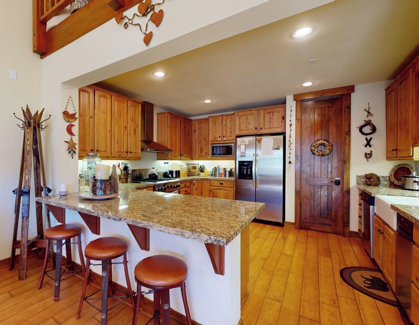 A kitchen with wooden cabinets, a stainless steel refrigerator, and a granite countertop.