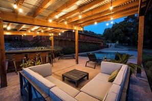 An outdoor patio with a wooden pergola, seating area, and a pool. - Serene Vineyard Chateau with Pool, Hot Tub, BBQ (Carmel Valley)