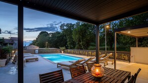 A covered outdoor area with a pool, lounge chairs, and a table with a candle.