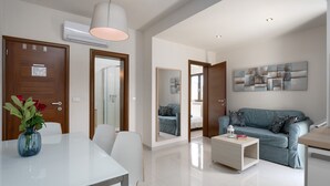 A modern living room with a sofa, a coffee table, and a dining area with a table and chairs.