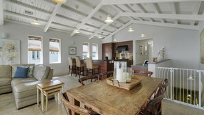 A spacious living area with a wooden dining table, a sofa, and a kitchen in the background.
