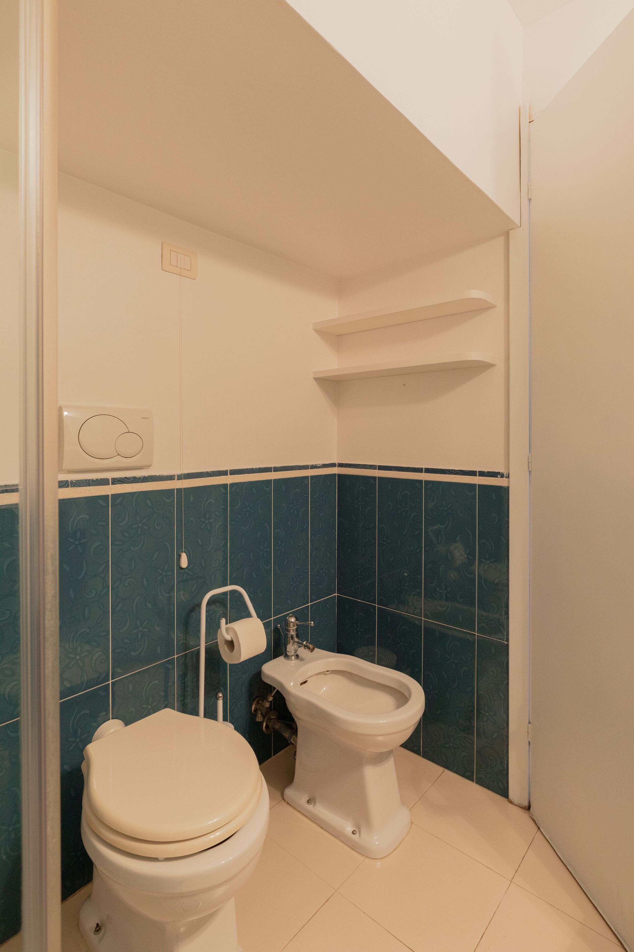 Ein Badezimmer mit Toilette, Bidet und Handtuchhalter.