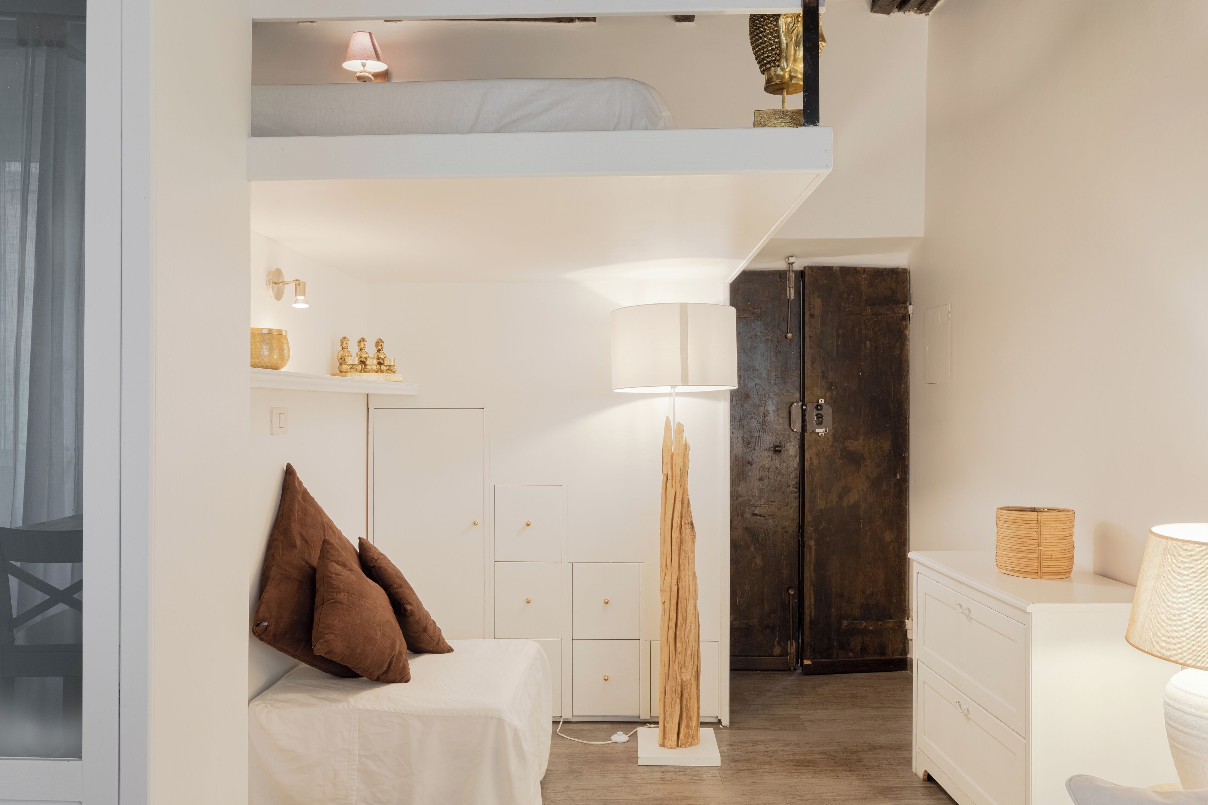 Une chambre à coucher moderne et compacte, équipée d’un lit superposé, de tables de chevet, d’une armoire et d’une grande sculpture en bois décorative.