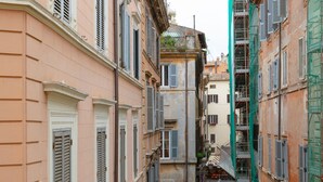 Una stretta via fiancheggiata da edifici storici con persiane chiuse e un percorso pedonale centrale.