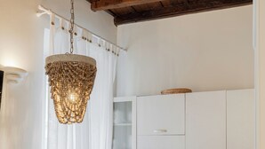 Una cucina con mobili bianchi, soffitto in legno e lampadario.