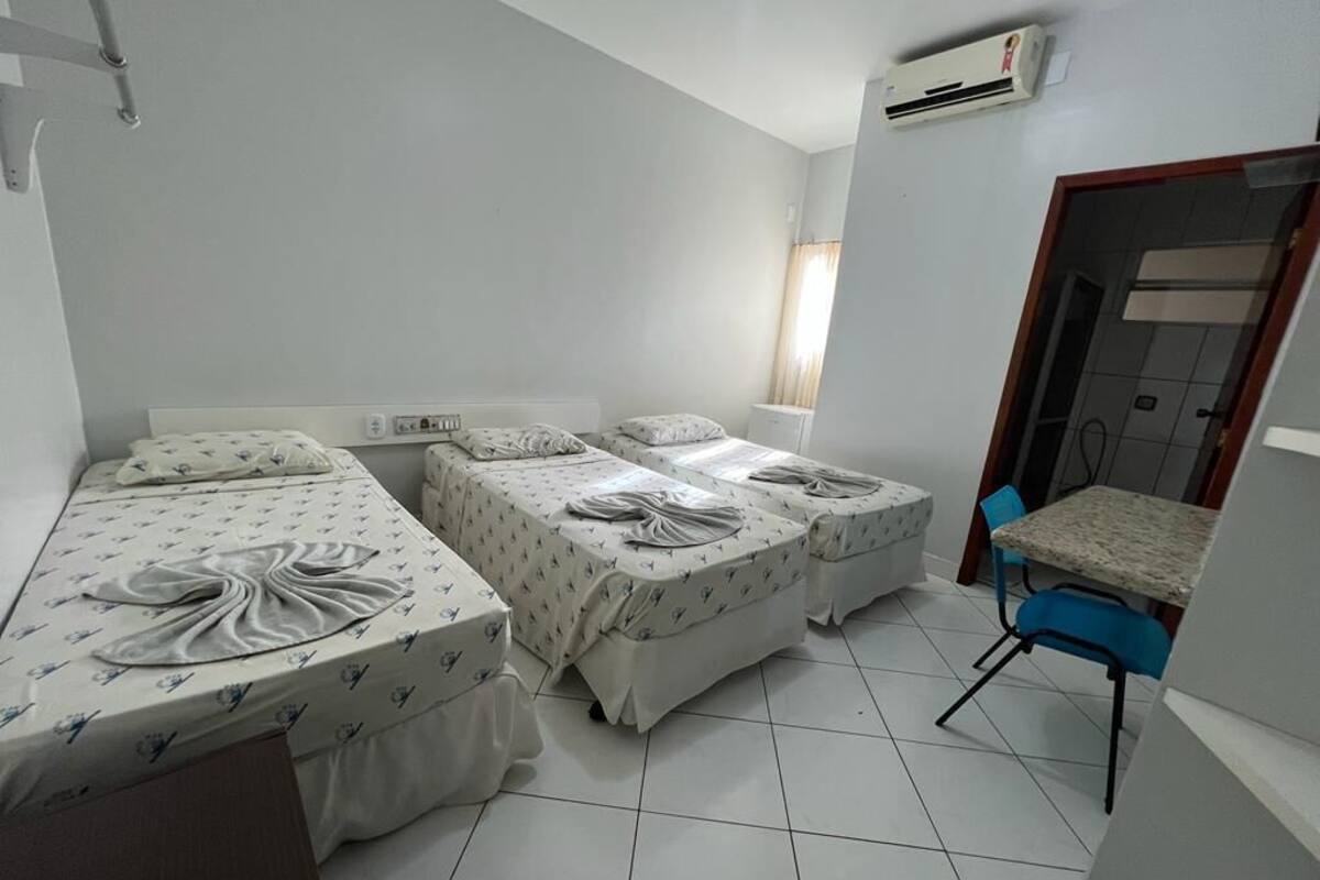 Ein Hotelzimmer mit zwei Einzelbetten, einem kleinen Tisch und einem Stuhl.
