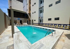 A rectangular swimming pool with a tiled deck, surrounded by a building with a tiled border and a balcony. - Hotel Mangabeiras Express (Maceió)