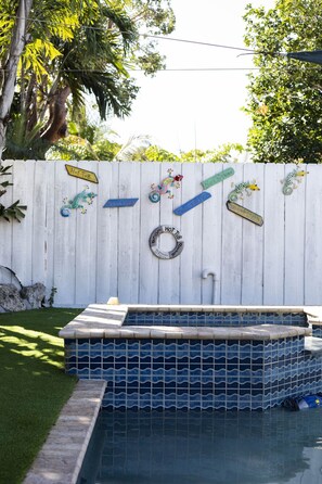 A swimming pool with a white fence decorated with signs and a metal ring. - Superb Keys home w/heated pool, jacuzzi, fast wifi & more! (Tavernier)