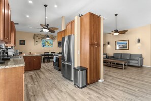 A modern kitchen with a central island, wooden cabinets, stainless steel appliances, and a dining area with a table and chairs. - Superb Keys home w/heated pool, jacuzzi, fast wifi & more! (Tavernier)
