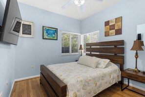 A bedroom with a bed, a nightstand, a lamp, a ceiling fan, and artwork on the walls. - Superb Keys home w/heated pool, jacuzzi, fast wifi & more! (Tavernier)