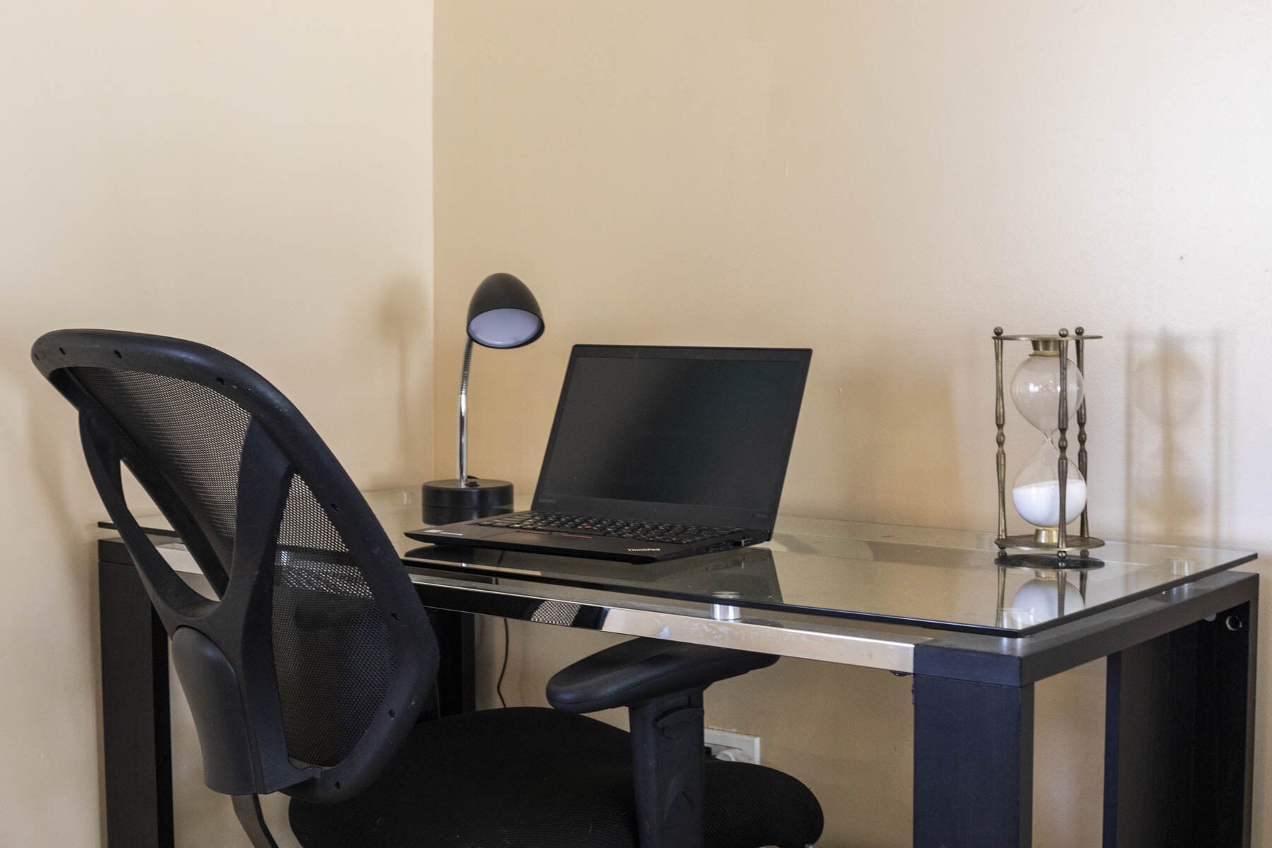 A workspace with a laptop, a desk lamp, and an hourglass.