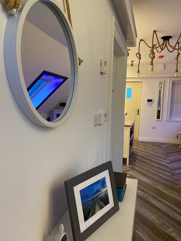 A hallway with a round mirror, a framed picture, and a door leading to another room.