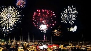 Ein Yachthafen mit vertäuten Booten bei Nacht, beleuchtet von Sternenfeuerwerk am Himmel.