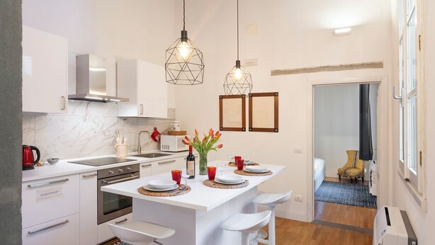 Een moderne keuken met een houten plafond, witte kasten, een centraal eiland met barkrukken en een dakraam.